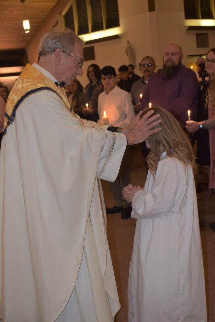 Fr. Thomas welcomes four confirmands into the Church