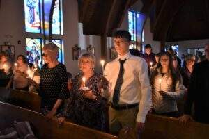 Parishioners hold candles during the beginning of Mass at the Easter Vigil in Columbiana