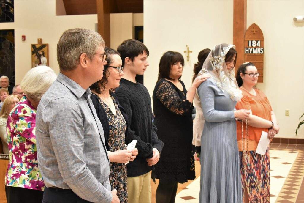 Candidates and their godparents stand in front of the altar.