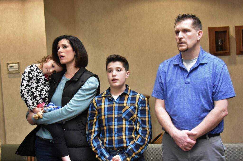 A family of four sings a hymn on Good Friday at St. William Parish