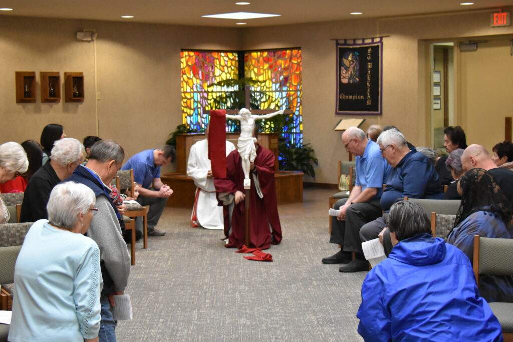 Congregation kneels in front of the cross at St. William Parish in Champion