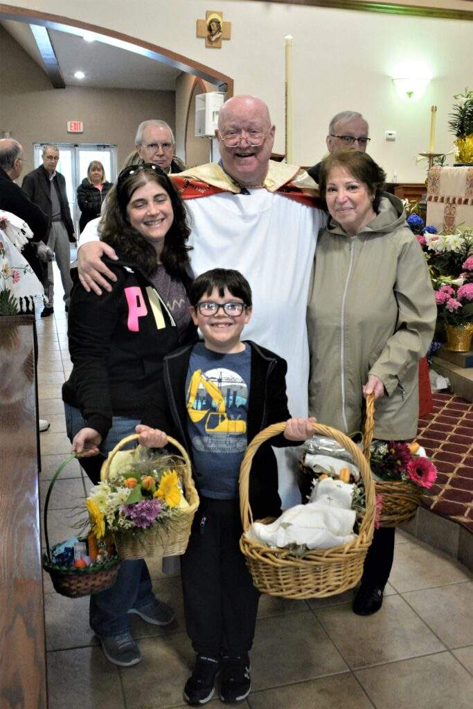 Fr. Kelly poses with a family and their Easter Baskets at the Blessing of Easter Food at St. Rose.