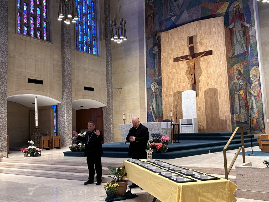 Bishop Bonnar stands near the altar with his hands raised in blessing