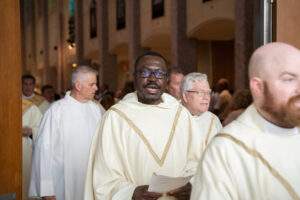 Priest holding worship aid sings as he exits the cathedral