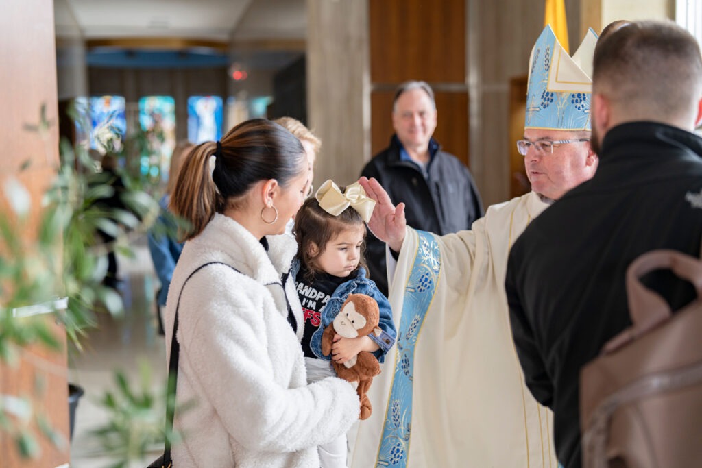 Bishop Bonnar blesses young child at the end of the White Mass. Photo by Brian Keith.