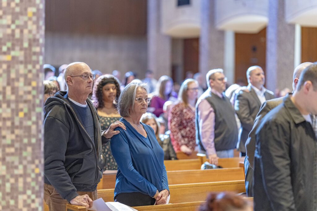 Man stands with his hand on woman's shoulder during the Rite of Election. Photo by Brian Keith.