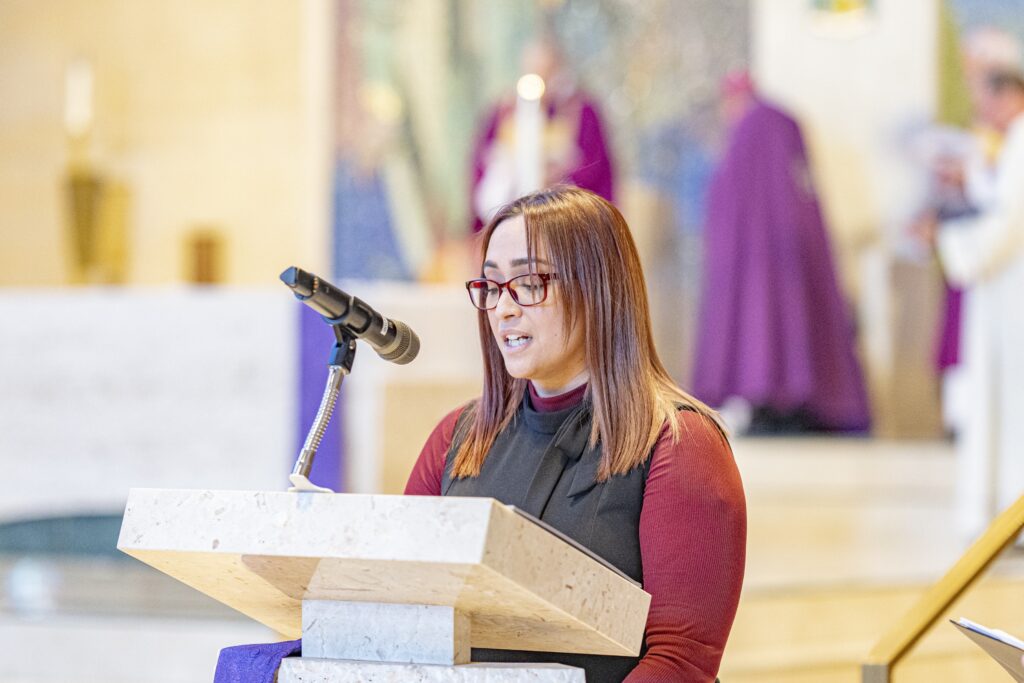 Woman stands at the cantor stand during the Rite of Election. Photo by Brian Keith.