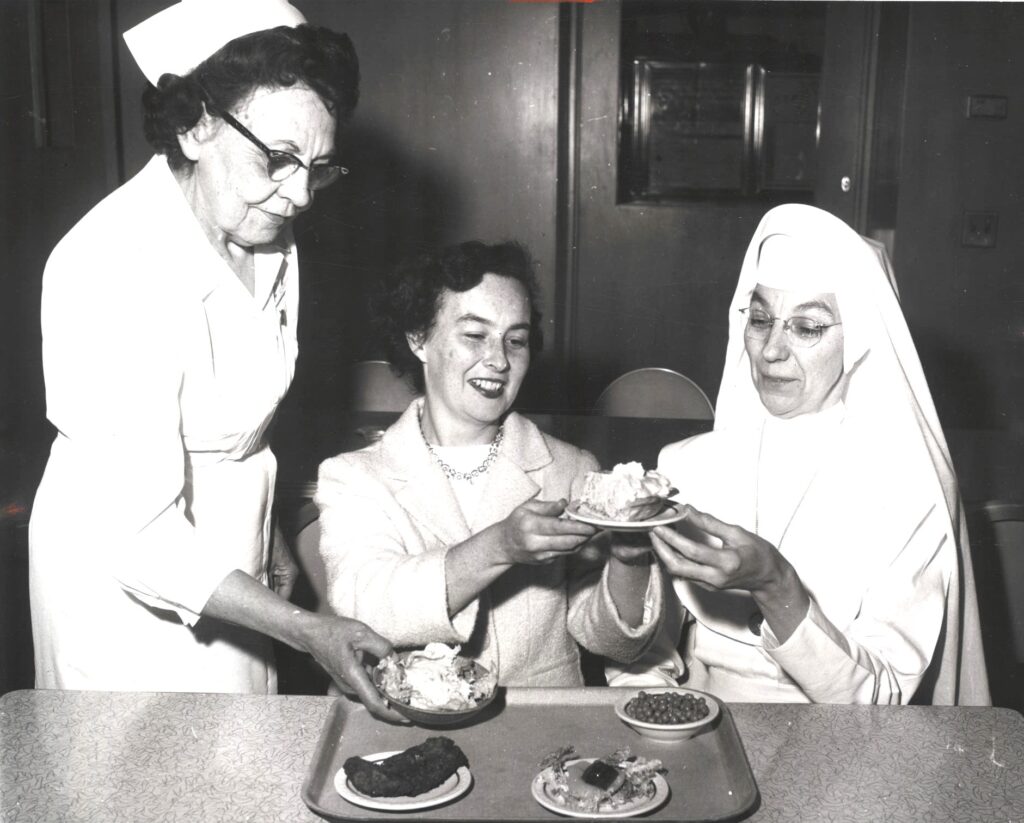 A nurse, nun and businesswoman examine food. 
