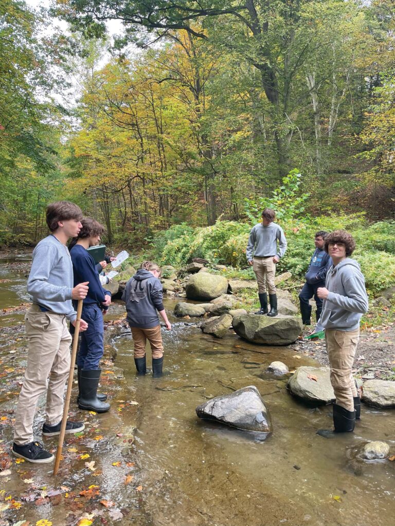 Six students wade in a stream in Ashtabula County.