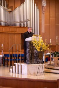 Priest stands at the ambo, delivering a homily. Photo by Courtney Poullas.