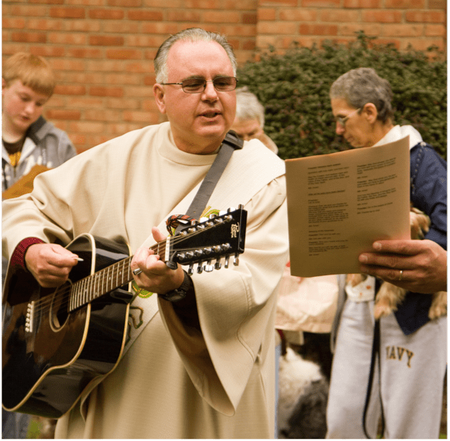 Man in vestment, playing guitar outside