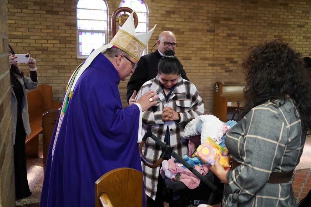Bishop Bonnar blesses a baby at the fourth annual hispanic summit. Photo by paulina montaldo.