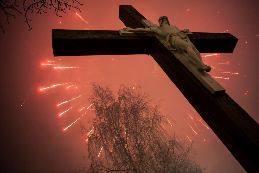 Cross standing in front of a July 4 fireworks display.
